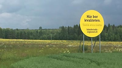 en rund och gul skylt på en äng. på skylten står det här bor kvaliteten.