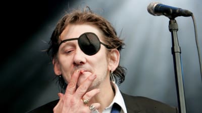 Shane MacGowan savuketta imien lavalla.