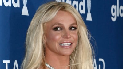 Britney Spears ler och tittar åt sidan medan hon poserar på röda mattan.
