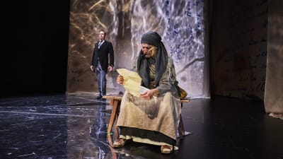 Mor Östman (Anna Lemmetti-Vieri) har fått brev från Amerika. Johannes Smeds (Ville Härkönen) i bakgrunden.
