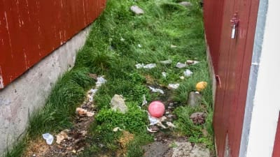 En liten gränd mellan två hus där skräp, toalettpapper och avföring finns.