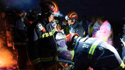 Räddningsarbetare bär en person på bår efter att extremväder slagit till under ett ultramaraton i provinsen Gansu i Kina.
