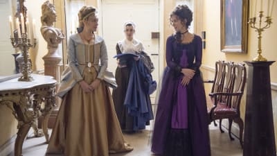 Två vackert klädda kvinnor konverserar artigt i en vacker hall
