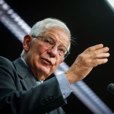 Joseph Borrell i närbild, håller handen lyft framför sig när han talar inför en mikrofon. 