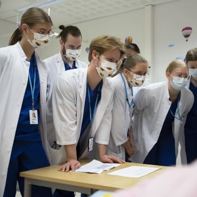 Lääketieteen opiskelijat ja lastenkirurgi Susanna Porela-Tiihonen katsovat tietokoneen näyttöä.