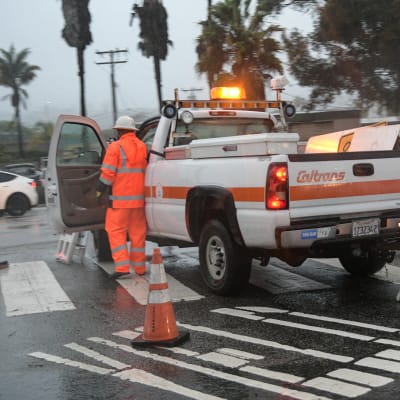 En man i orange regnkläder stiger in i en bil.