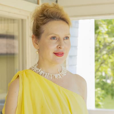 Opperalaulaja Marie Finne-Bray katsoo aurinkoisella kuistilla kameran ohi.
