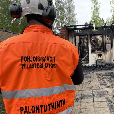 Pohjois-Savon pelastuslaitoksen palotutkija palaneen rivitalohuoneiston edessä. 