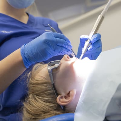 Hammaslääkäri puhdistaa ja tutkii lapsen hampaita.