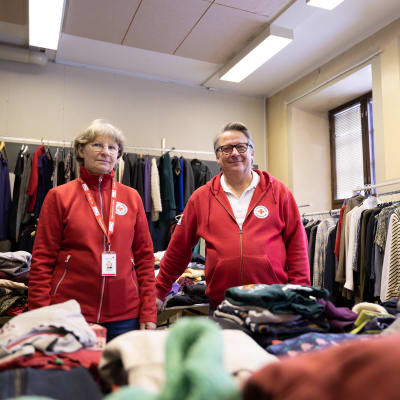 Röda Korsets frivilligarbetare i ett rum omgivna av kläder