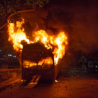 En av de många bussar som demonstranter brände upp under bråken på fredag kväll i Santiago. 