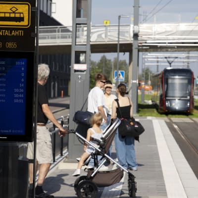 Ihmiset odottavat saapuvaa raitiovaunua Santalahden pysäkillä Tampereella.