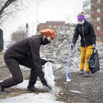 Juni Sinkkonen ja Eveliina Korkiatupa keräävät pihdeillä roskia maasta.
