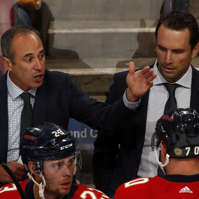 Tuomo Ruutu Florida Panthersin vaihtopenkin takana. Hänen vieressään toinen apuvalmentaja Derek MacKenzie antaa ohjeita pelaajille.