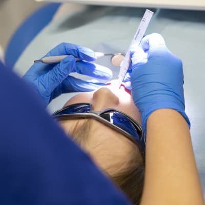 En tandläkare undersöker och mäter tänderna på ett barn.