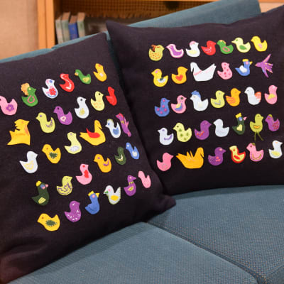Två kuddar med färgglada fåglar i en soffa