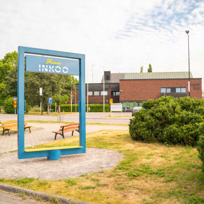 Ingå kyrkby sommaren 2023 med kommungården i bakgrunden och en skylt som föreställer en blå ram, "Iloinen Inkoo".