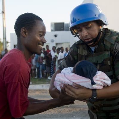 Bolivisk FN-soldat överlämnar spädbarn till dess far.