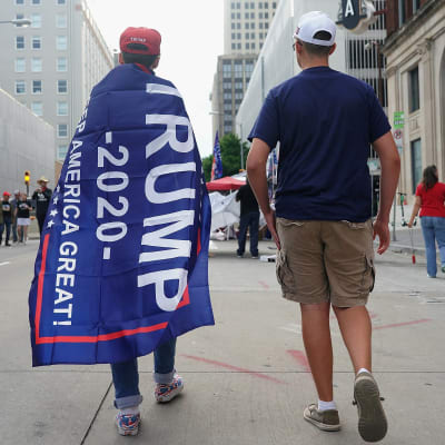 En Trumpsupporter inlindad i en kampanjfana promenerar på gatan i Tulsa i Oklahoma.