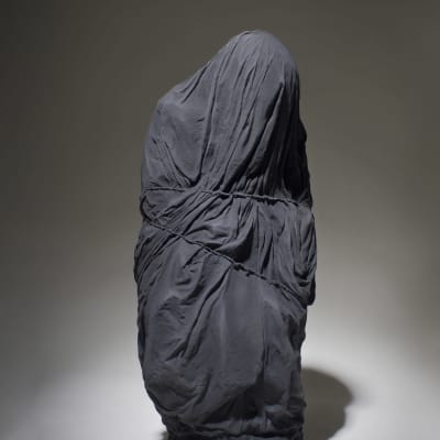 Tiia Matikaisen teos Nobody. Teoksessa istuva ihminen on kääritty mustaan kaapuun. Edes silmiä ei näy.
