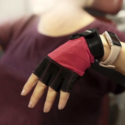 Naisen käsi lepää kuntoharjoittelun jälkeen. Kädessä on sormet paljaaksi jättävä suojakäsine.