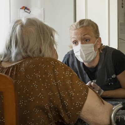 Lähihoitaja Emilia Vilokkinen keskustelee vanhuksen kanssa. 