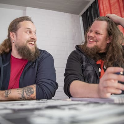 Roope-Santeri Nieminen ja Esa Turunen pöydän ääressä piirtämässä sarjakuvia iloisina.