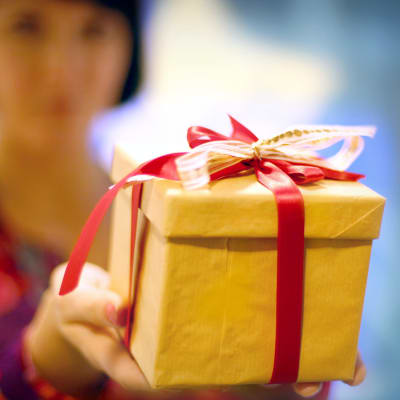 En kvinna håller upp en julgåva med sidenband.