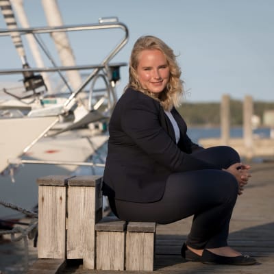 Michelle Grönlund sitter på en brygga. Båtar i bakgrunden. 