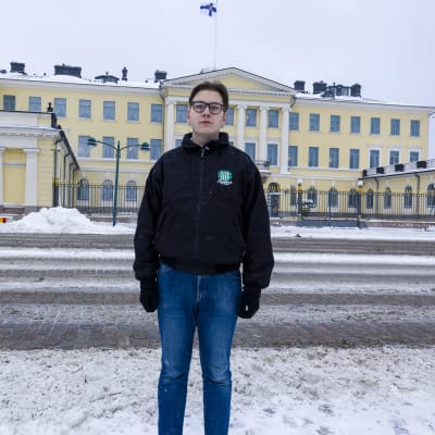Nuori mies lumisessa Helsingissä presidentin linnan edustalla.