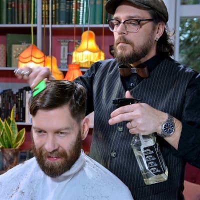 En man klipper en annan mans hår.