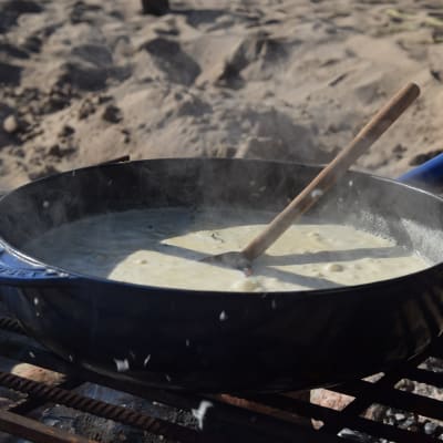 Senapssås i stekpanna på grillgaller på sandstranden.