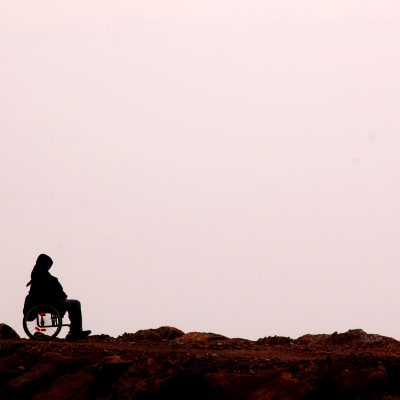Ensam person i rullstol vid havet. 