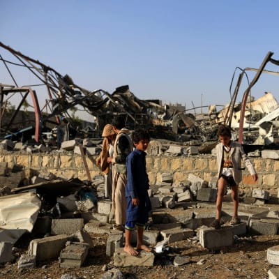 Barn samlar metallskrot vid en husruin efter en saudisk flygräd i Jemens huvudstad Sanaa den 20 januari 2019.