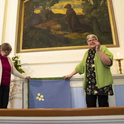 Seija Happonen ja Riitta Junnila-Savolainen asettelevat kirkkokangasta alttarille.
