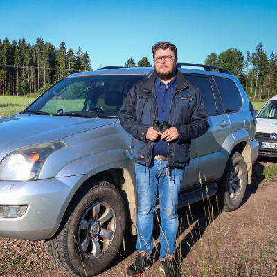 Tomas Nyström står vid sin bil intill en åker