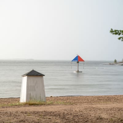 Simhus, strand, hav och en karusell i vattnet.