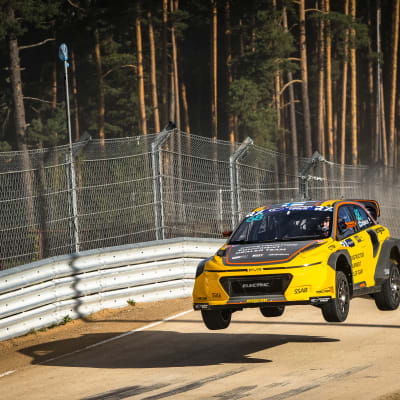 En rallycrossbil hoppar i en liten backe.