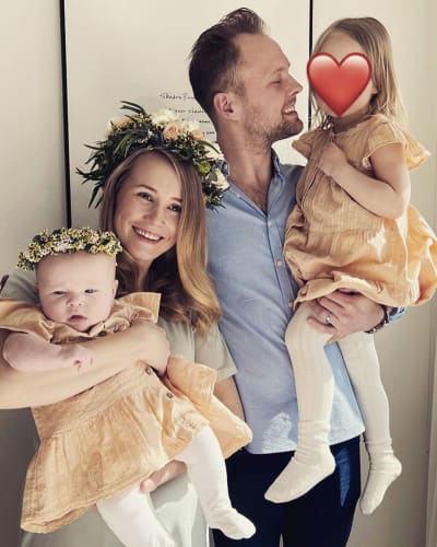 Familjeporträtt med en man, en kvinna, en liten flicka och en bebis. Kvinnan och bebisen har blomkrans på huvudet.