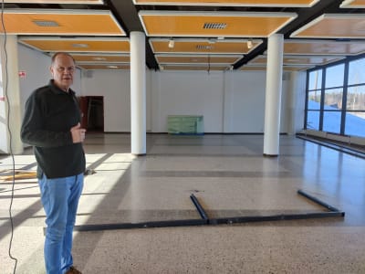 En man står i en stor aula som ska byggas om till bostäder. Han heter Markku Nikola.