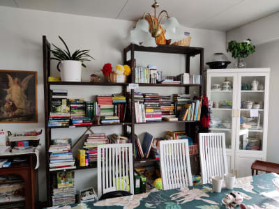 Ett bord med stolar och bakomdem en bokhylla med mängder av böcker.