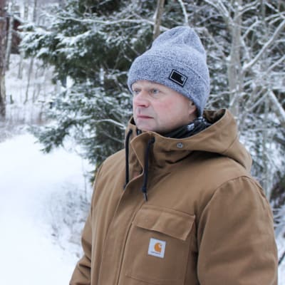 nicke står och funderar på en snöig väg, i bakgrunden syns anna-maija nordling och idyllisk vintermiljö