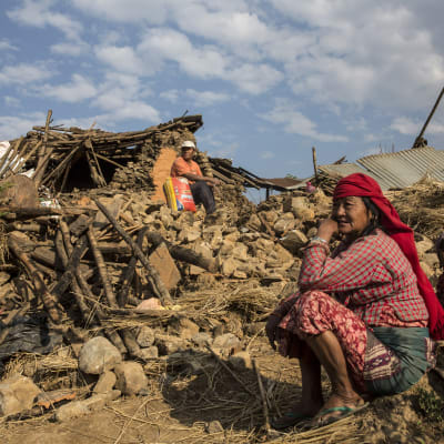 Nepalesisk familj vid ruinerna av sitt hem efter jordbävning