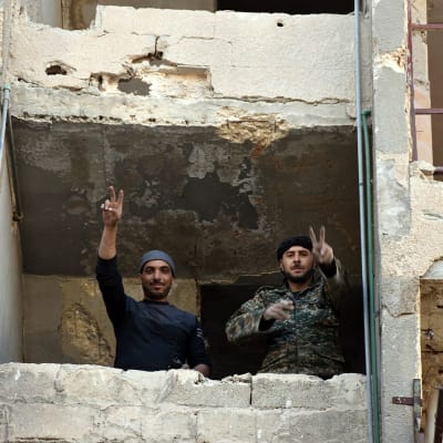 Syriska soldater gör segertecken i fönstret till ett rasat hus i Aleppo.