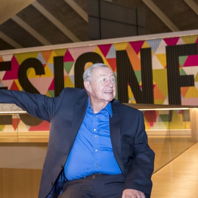 Terence Conran istuu museotilassa taustallaan teksti Designer