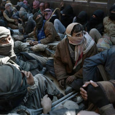 Män som lämnade IS sista fäste i Syrien och togs tillfånga sitter på ett lastbilsflak.