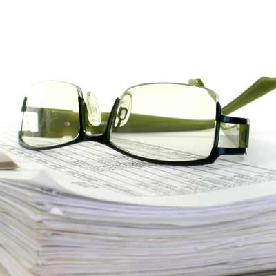 Ett par glasögon ligger på en hög med papper i en mapp.