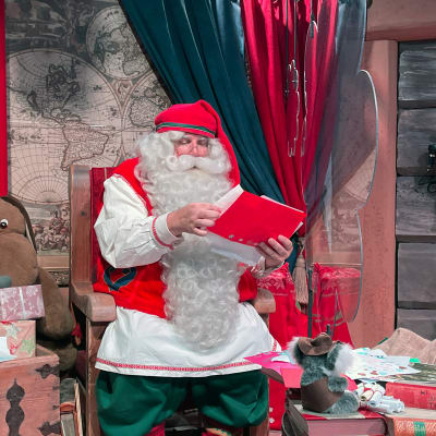 Joulupukki lukee kirjettä toimistossaan Napapiirin pajakylässä.