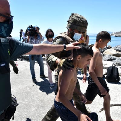 Sotilaat taluttavat maahan pyrkivää lasta Espanjan rannikolla.