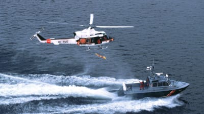 En sjöbevakningshelikopter och en sjöbevakninsbåt åker vid sidan om varandra.